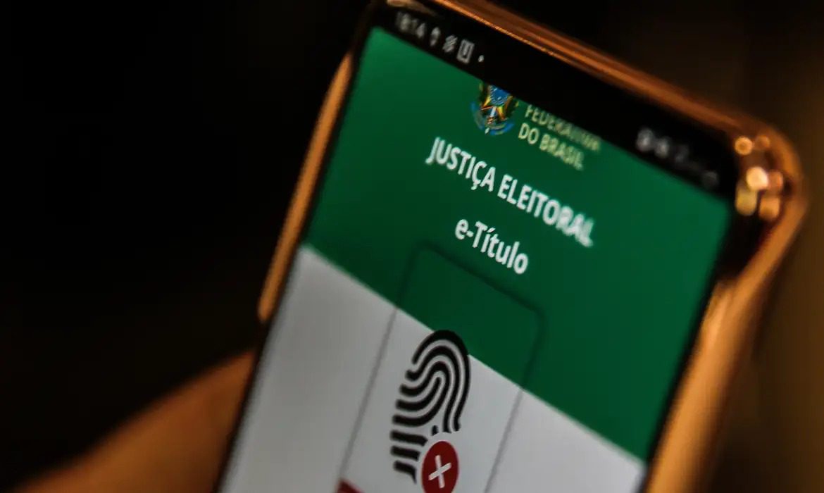 e-Título: eleitor tem até a véspera da eleição para baixar aplicativo aplicativo e-Título: baixe nas Plataformas Android e iOS; formulário Requerimento de Justificativa Eleitoral (formato PDF): apresente preenchido nas mesas receptoras de votos ou de justificativas instaladas para essa finalidade nos locais divulgados pelos Tribunais Regionais Eleitorais e pelos Cartórios Eleitorais (consulta a zonas eleitorais). Não é necessário anexar documentos que comprovem o motivo da ausência quando a justificativa for apresentada no dia da eleição. O histórico de justificativas eleitorais, contendo os respectivos pleitos em que a eleitora ou o eleitor estiveram ausentes, poderá ser consultado no aplicativo e-Título. O acesso ao aplicativo e-Título está disponível somente para quem está com o título eleitoral regular ou suspenso. No caso de utilização do Requerimento de Justificativa Eleitoral (RJE), é necessário apresentar também um documento oficial de identificação com fotografia (e-Título, carteira de identidade, identidade social, passaporte, certificado de reservista, carteira nacional de habilitação, carteira de trabalho ou outro documento de valor legal equivalente, inclusive carteira de categoria profissional reconhecida por lei) no local de votação ou de recepção de justificativas. Esses documentos são aceitos ainda que expirada a data de validade.