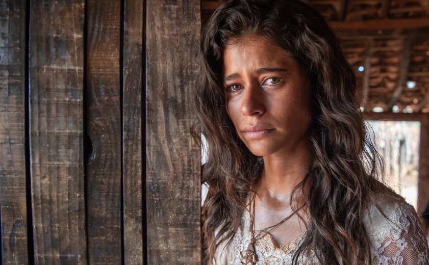 Isadora Cruz emocionada em cenário natural, representando sua experiência espiritual durante gravações da novela Guerreiros do Sol.