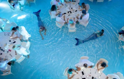 Jantar dentro de piscina com 'sereia' entre mesas viraliza e rende piadas no Brasil